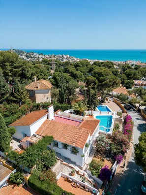 Um imóvel residencial com piscina, telhado de terracota e vista para o mar.