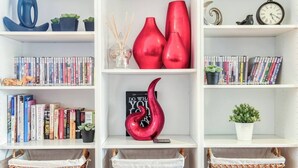 A bookshelf with books, decorative items, and a red sculpture.
