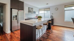 A modern kitchen with a central island, bar stools, a refrigerator, and a microwave.