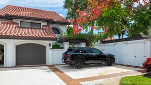 A house with a tiled roof, a garage, and a driveway. - 3-bedroom Jupiter condo in gated community (Jupiter)
