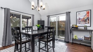 A dining area with a dark wooden table and chairs, a sign reading "Coffee Time", and a view through large glass doors to the outdoors. - 3BdRoom Home w/ Hot Tub + Game Room (Galena)