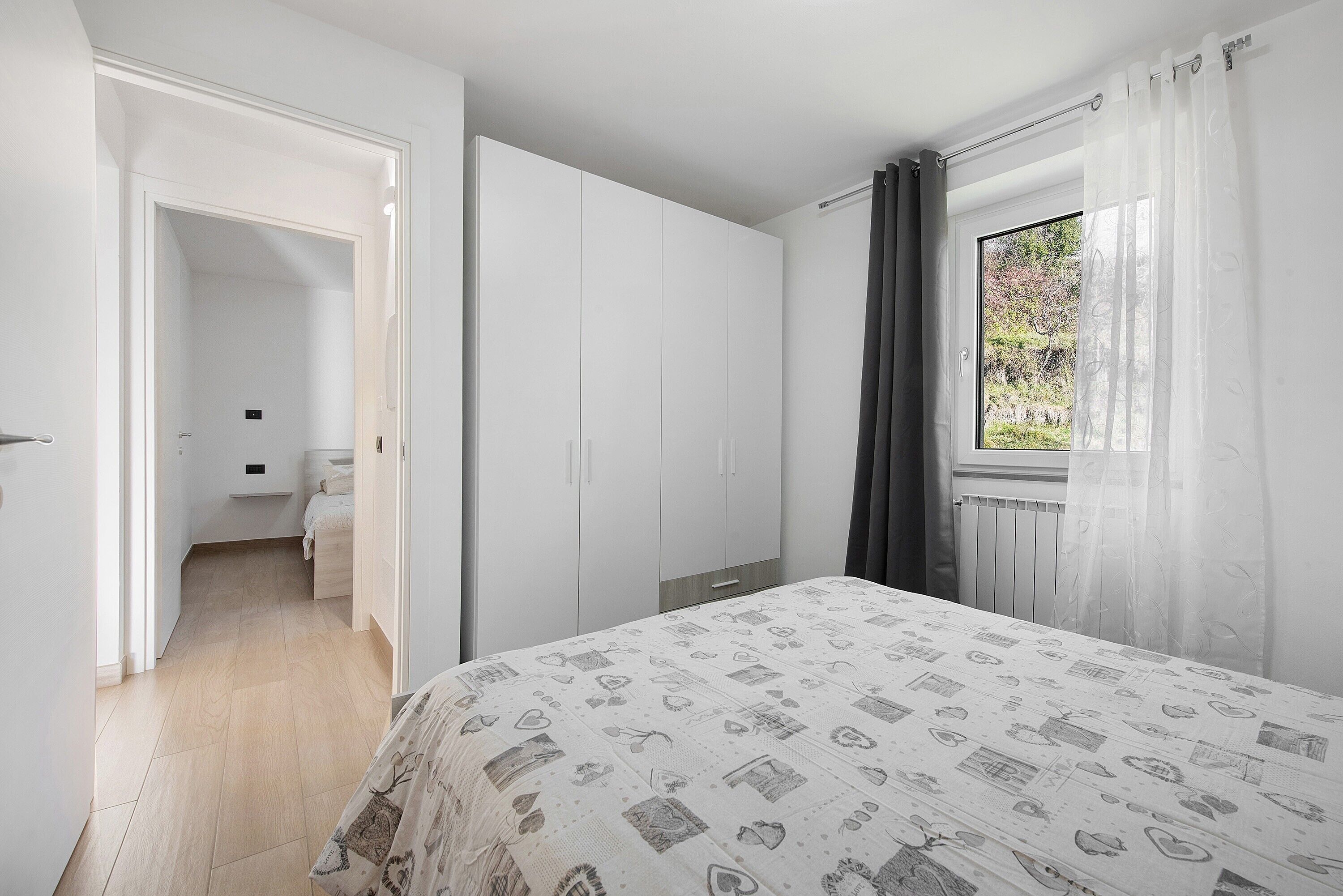 Une chambre à coucher avec un lit, une armoire et une fenêtre avec des rideaux.