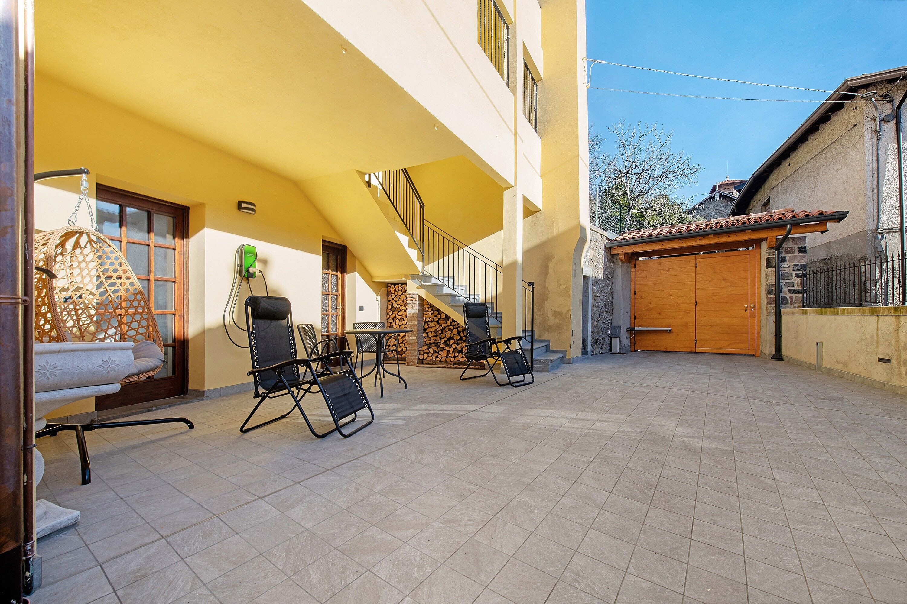 Un patio con mesas al aire libre, una puerta de madera y una escalera que sube a un nivel superior.