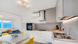 Een moderne keuken met witte kasten, een RVS-spoelbak en een eethoek met een witte tafel en gele stoelen.