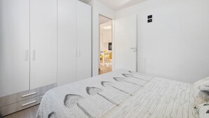 Een slaapkamer met een bed, een garderobe en een deur naar een eetgedeelte.