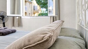 A bedroom with a bed, a window, and a view of buildings outside. - Apt Tamarells Pinaret 350m to the beach. By JS Vil (Puerto Pollensa)