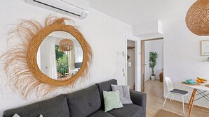 A modern living room with a grey sofa, a round mirror, and a dining area with a white chair and table. - Apt Tamarells Pinaret 350m to the beach. By JS Vil (Puerto Pollensa)