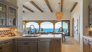 Een ruime keuken met een groot schiereiland, moderne apparaten en uitzicht op zee.