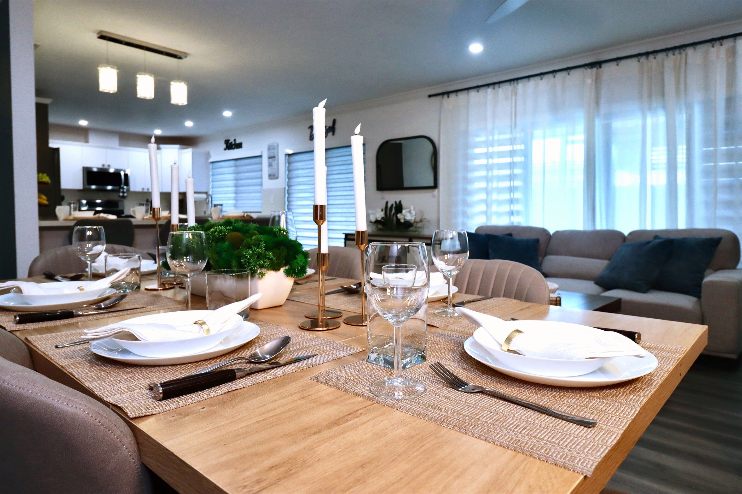 A dining area with a wooden table set for four, including plates, cutlery, and glasses.