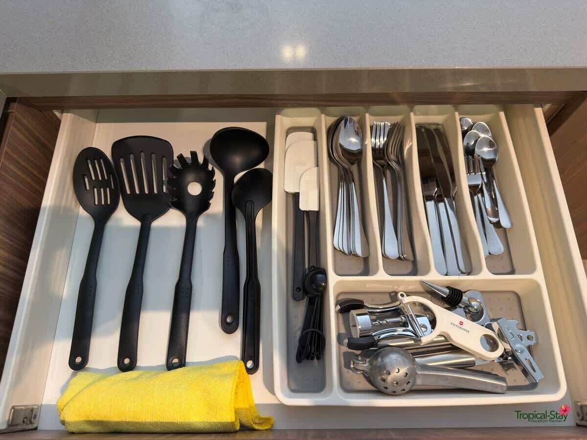 Un tiroir contenant des ustensiles de cuisine, notamment des spatules, des cuillères, des couteaux et une râpe.