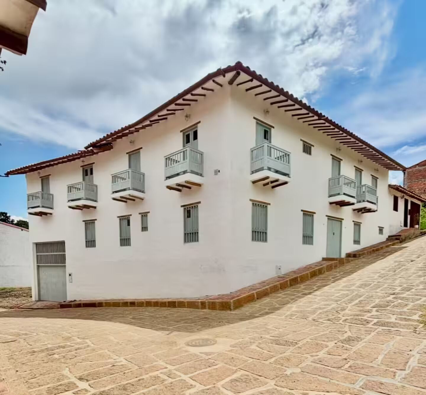 A multi-story building with balconies and a stone-paved courtyard.