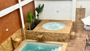 A rectangular pool with a hot tub, surrounded by stone walls and a tiled patio. - Casa Monica - Apt Astromelia (Barichara)