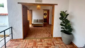 A hallway with a wooden door, a potted plant, and a sign reading "Astromelia". - Casa Monica - Apt Astromelia (Barichara)