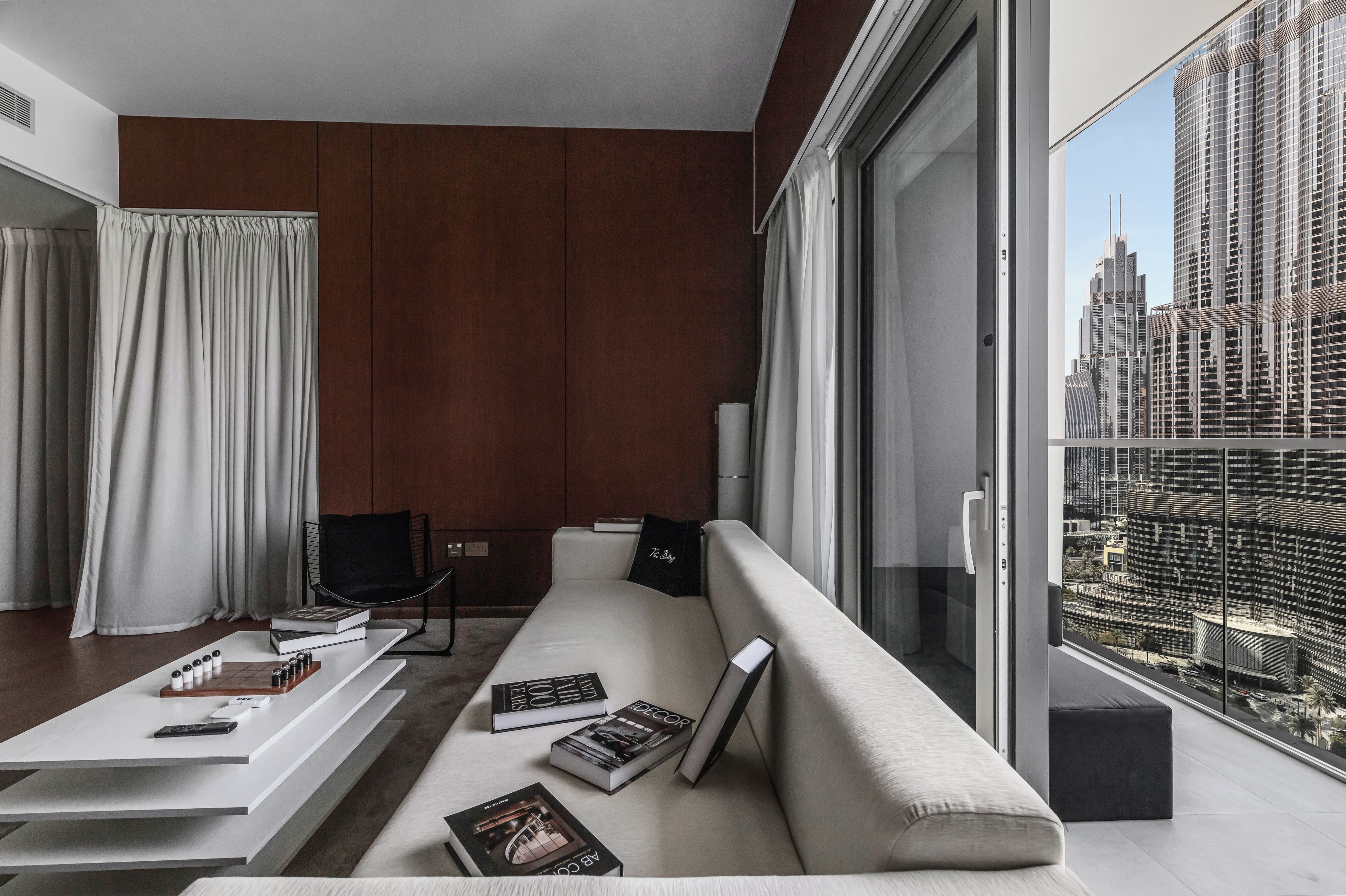 A modern living room with a sofa, a coffee table, and a chair. There are books and a remote control on the table.