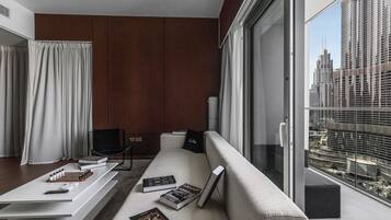A modern living room with a sofa, a coffee table, and a chair. There are books and a remote control on the table.