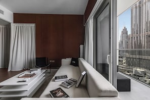 A modern living room with a sofa, a coffee table, and a chair. There are books and a remote control on the table. - Elegant Stay with Burj Khalifa View (Dubai)