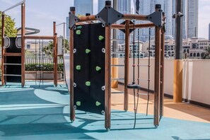 A rooftop playground with climbing structures and swings, surrounded by a cityscape. - Elegant Stay with Burj Khalifa View (Dubai)