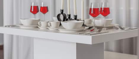 Ein weißer Tisch mit Weingläsern, weißen Kerzen und Besteck.
