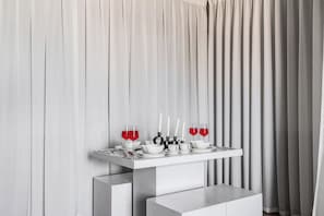 A modern dining setup with a white table, two glasses of red liquid, white candles, and a minimalist design. - Elegant Stay with Burj Khalifa View (Dubai)