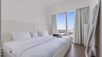 A hotel room with a large bed, a view of the city, and a window with curtains.