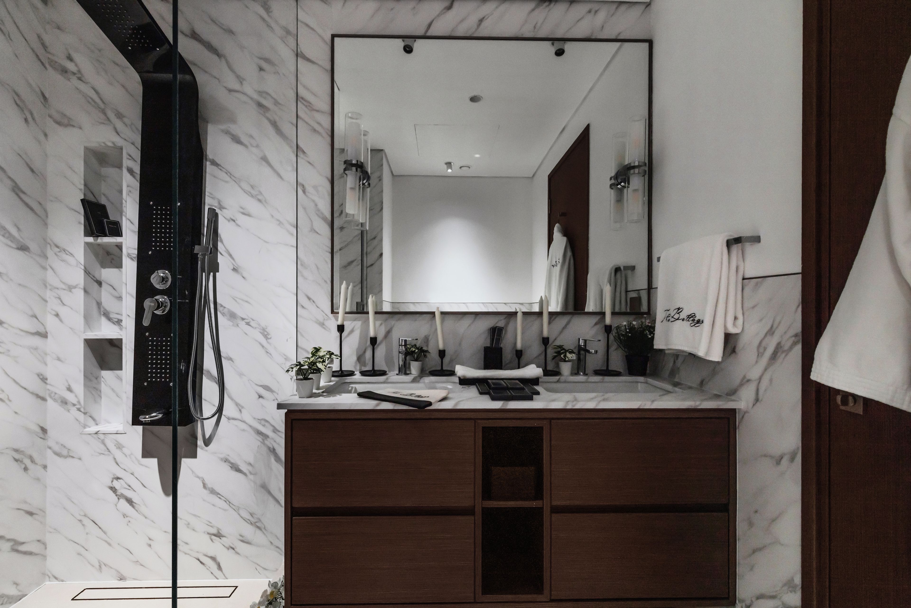 Un baño moderno con tocador de mármol, un espejo grande y cabina de ducha.