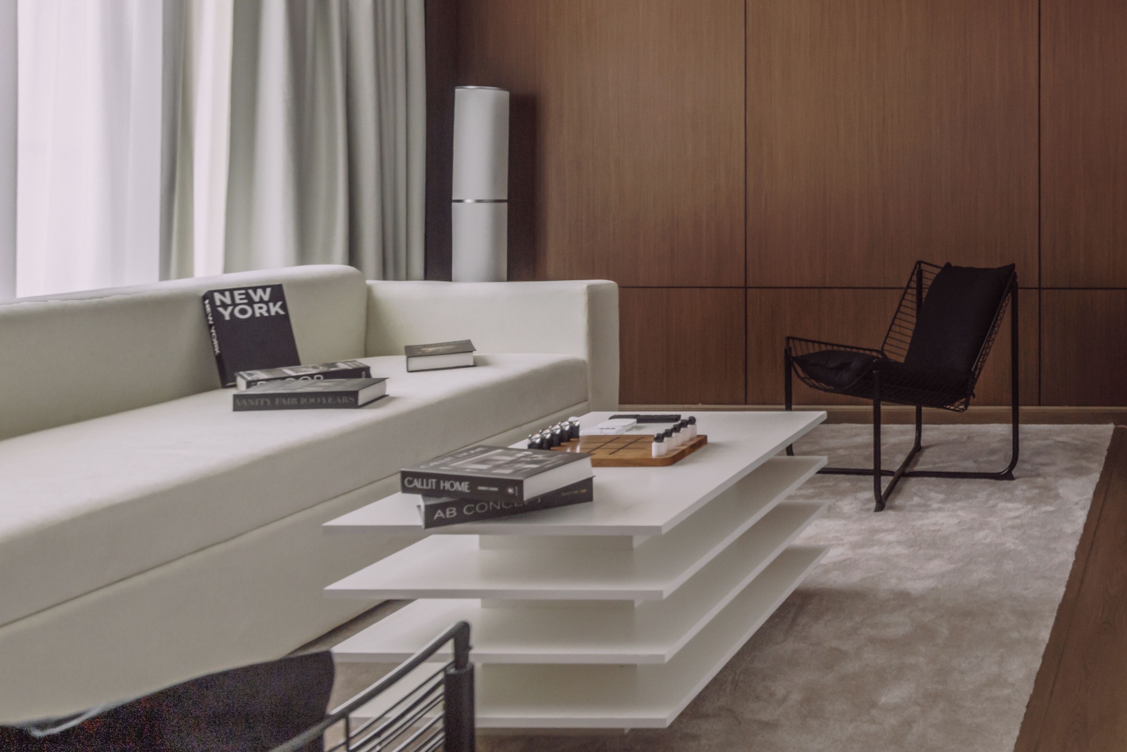 Un salon moderne avec un canapé blanc, un fauteuil noir et une table basse sur laquelle sont posés des livres.