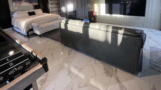 A modern hotel room with a bed, a sofa, a TV, and a fireplace.