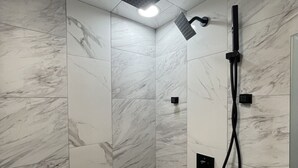 A modern shower with a square showerhead and a handheld shower attachment.