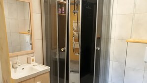 Een badkamer met een douche met glazen wand, een wastafel met spiegel, en een toilet.