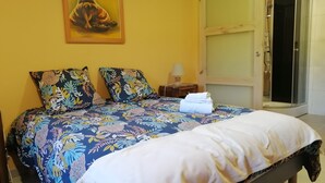 Een bed met een bloemenbedekking, twee kussens en een opgevouwen handdoek.