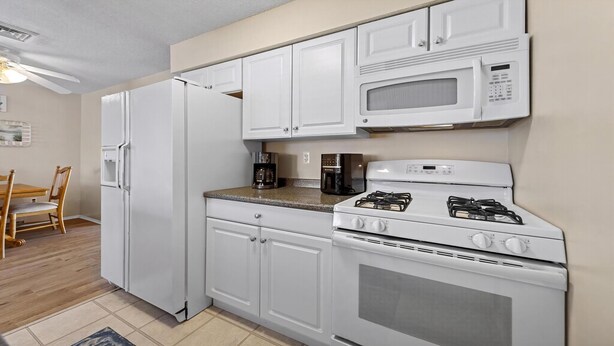 A kitchen with white cabinetry, a refrigerator, a microwave, a coffee maker, and a stove. - Lagoonfront Home in Beach Haven West with a pool & kayaks! (Manahawkin)