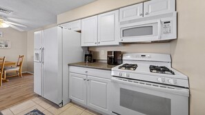 A kitchen with white cabinetry, a refrigerator, a microwave, a coffee maker, and a stove. - Lagoonfront Home in Beach Haven West with a pool & kayaks! (Manahawkin)