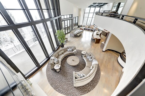 Un interior espacioso y moderno con una zona de estar circular, ventanas amplias y un techo alto.