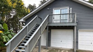 Een tweelaags huis met een veranda, een trap en twee garagepoorten.