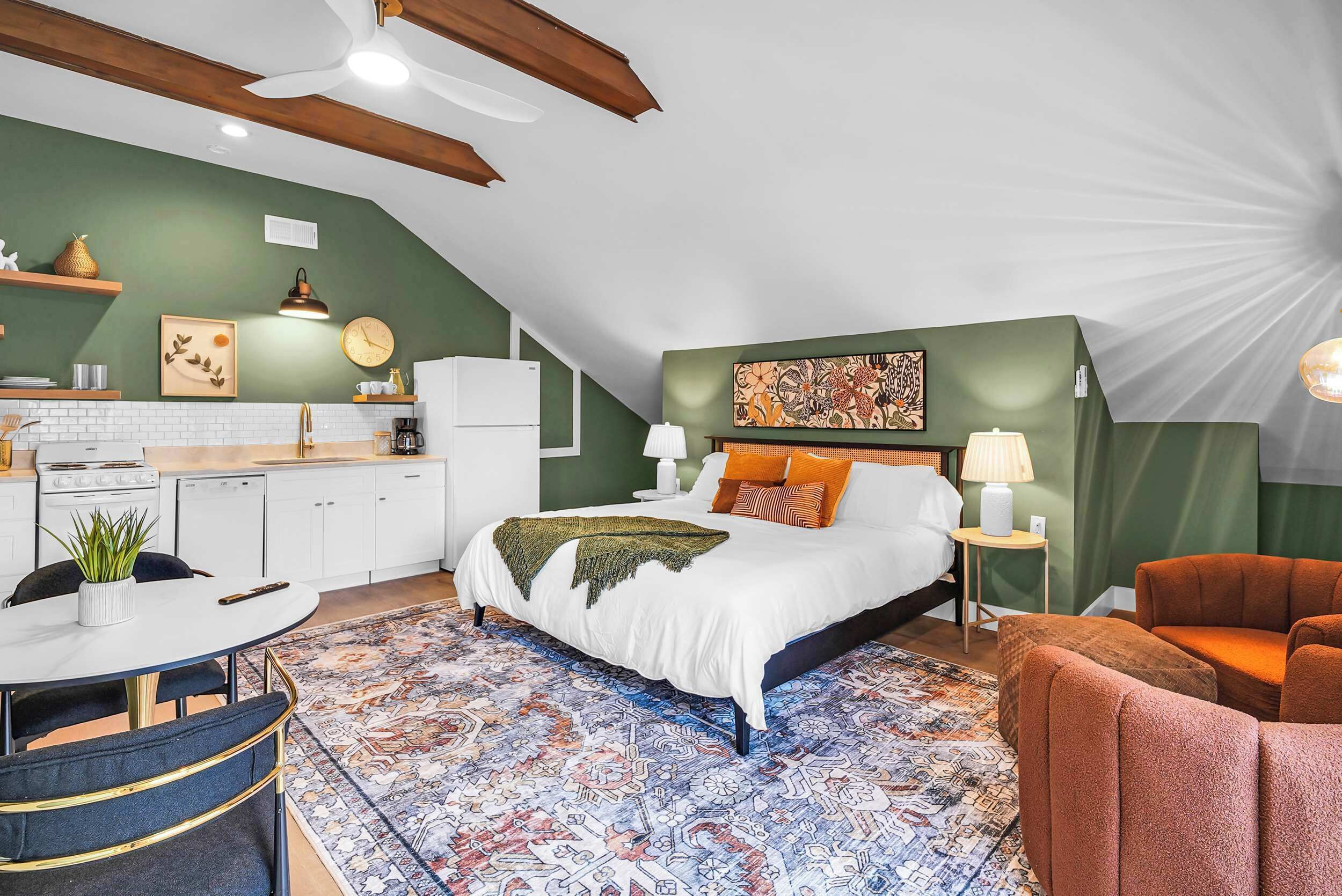 A modern bedroom with a large bed, a dining area, and a kitchenette.