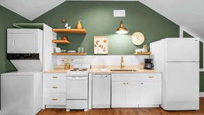 Een keuken met witte apparaten, houten planken en een groene accentmuur.