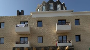 A multi-story building with a stone facade, multiple balconies, and a central entrance with glass doors. - Casa Clara apartment with sea view on the beach (Chloraka)