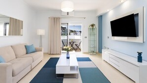 Un salon moderne avec un canapé, une table basse, un téléviseur et un balcon offrant une vue agréable.