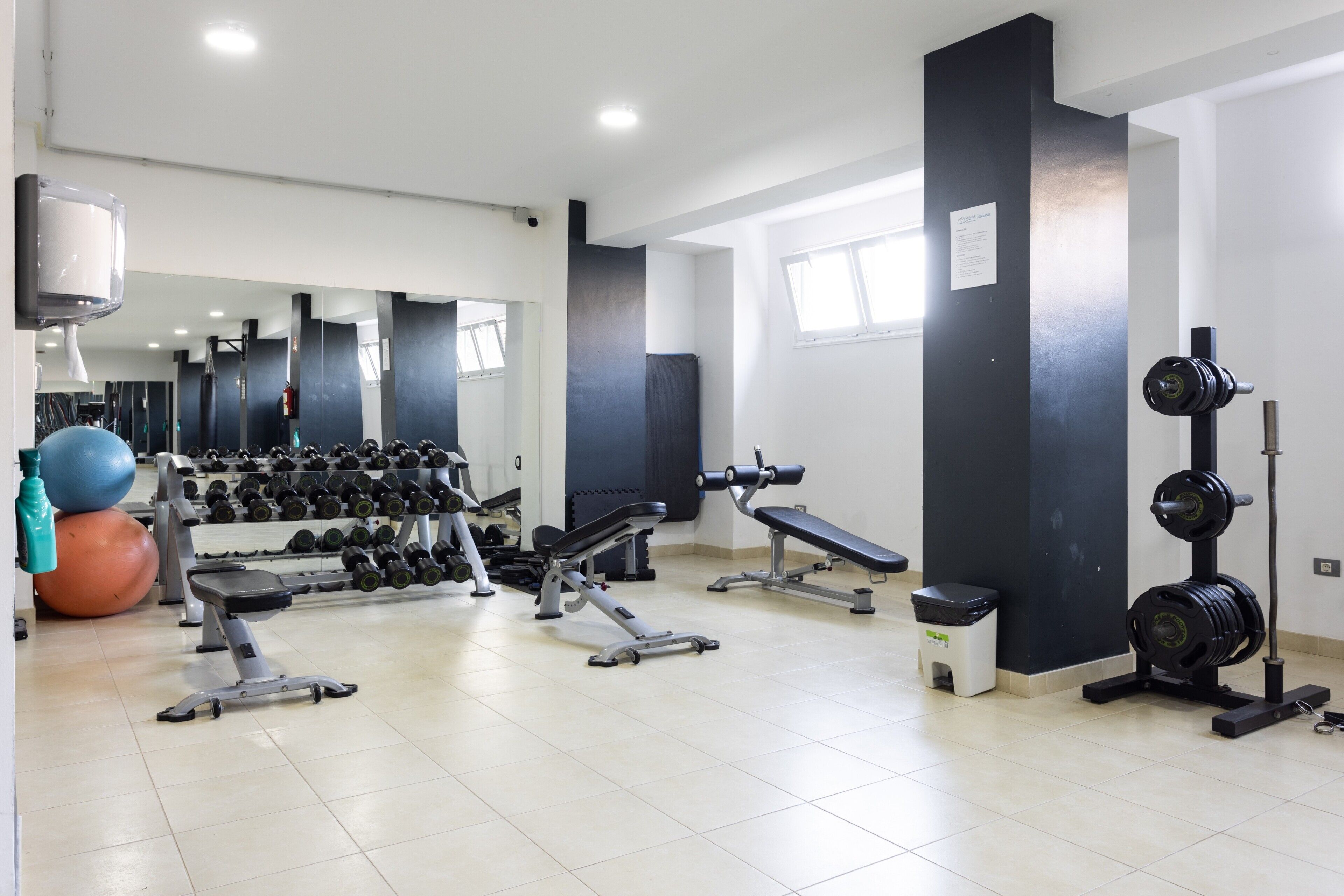 A gym with exercise equipment, a mirror, and a window.