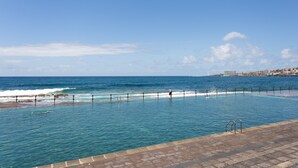 Une piscine offrant une vue sur l’océan et sur les bâtiments d’une ville lointaine.