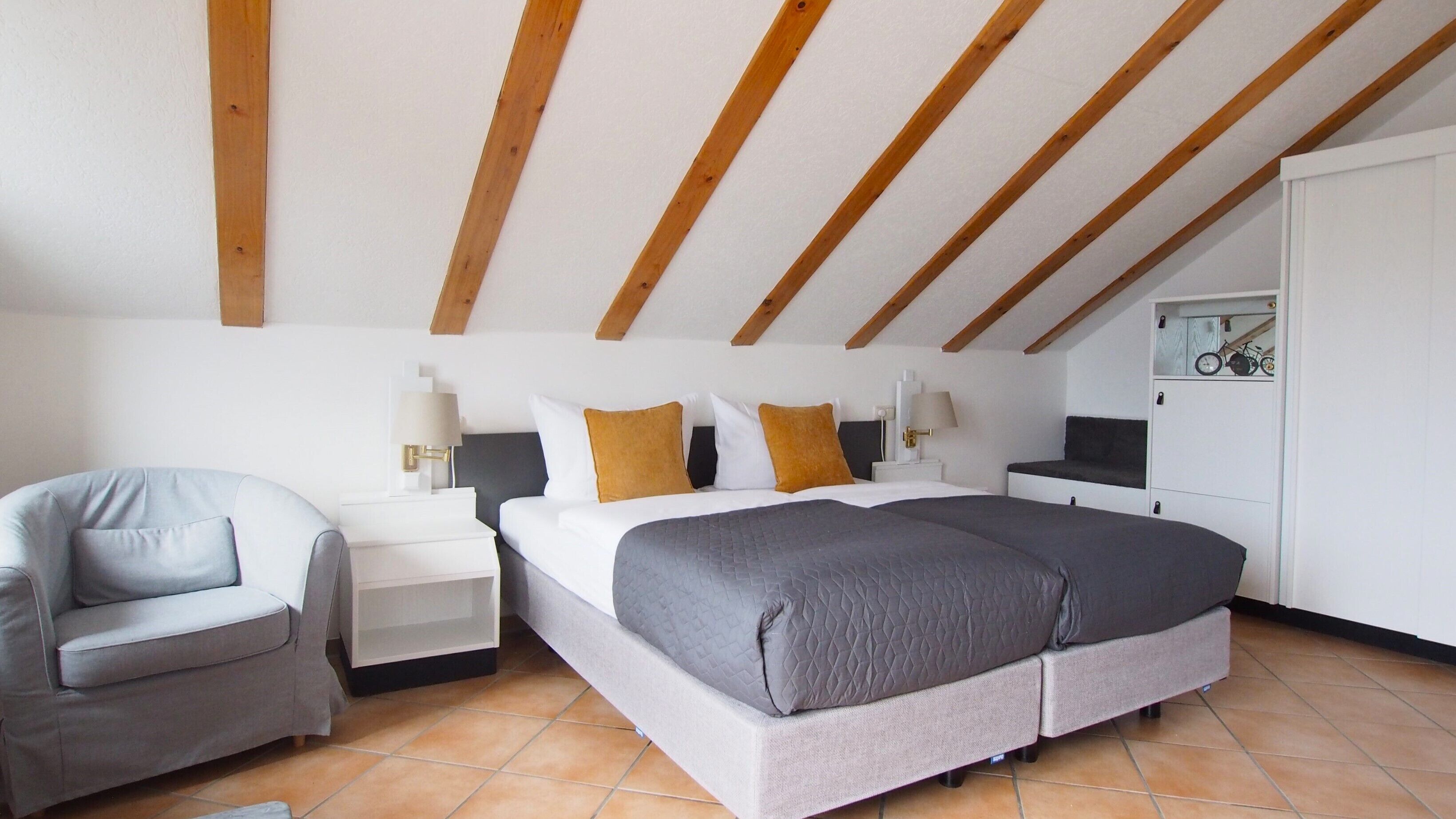 A bedroom with a bed, bedside tables, a chair, and a wardrobe.