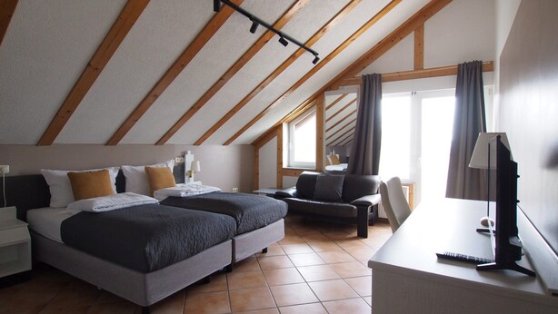 Un dormitorio con dos camas, un escritorio, una silla y un ventanal con cortinas.