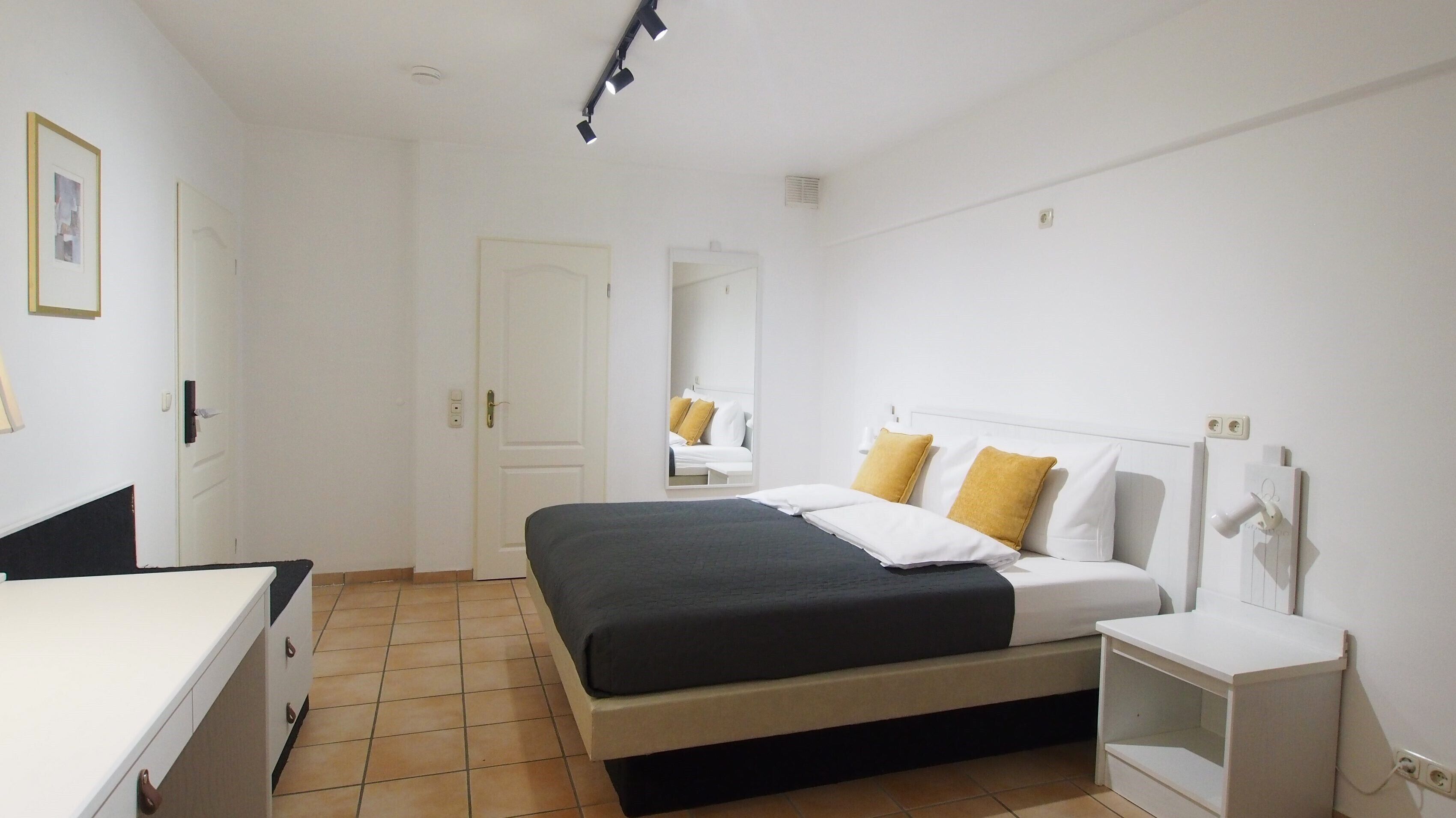 A bedroom with a bed, bedside table, and a mirror.