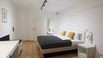 A bedroom with a bed, bedside table, and a mirror.