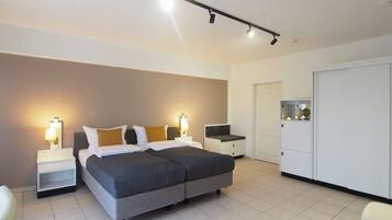 A modern hotel room with a large bed, bedside tables, a desk, and a wardrobe.