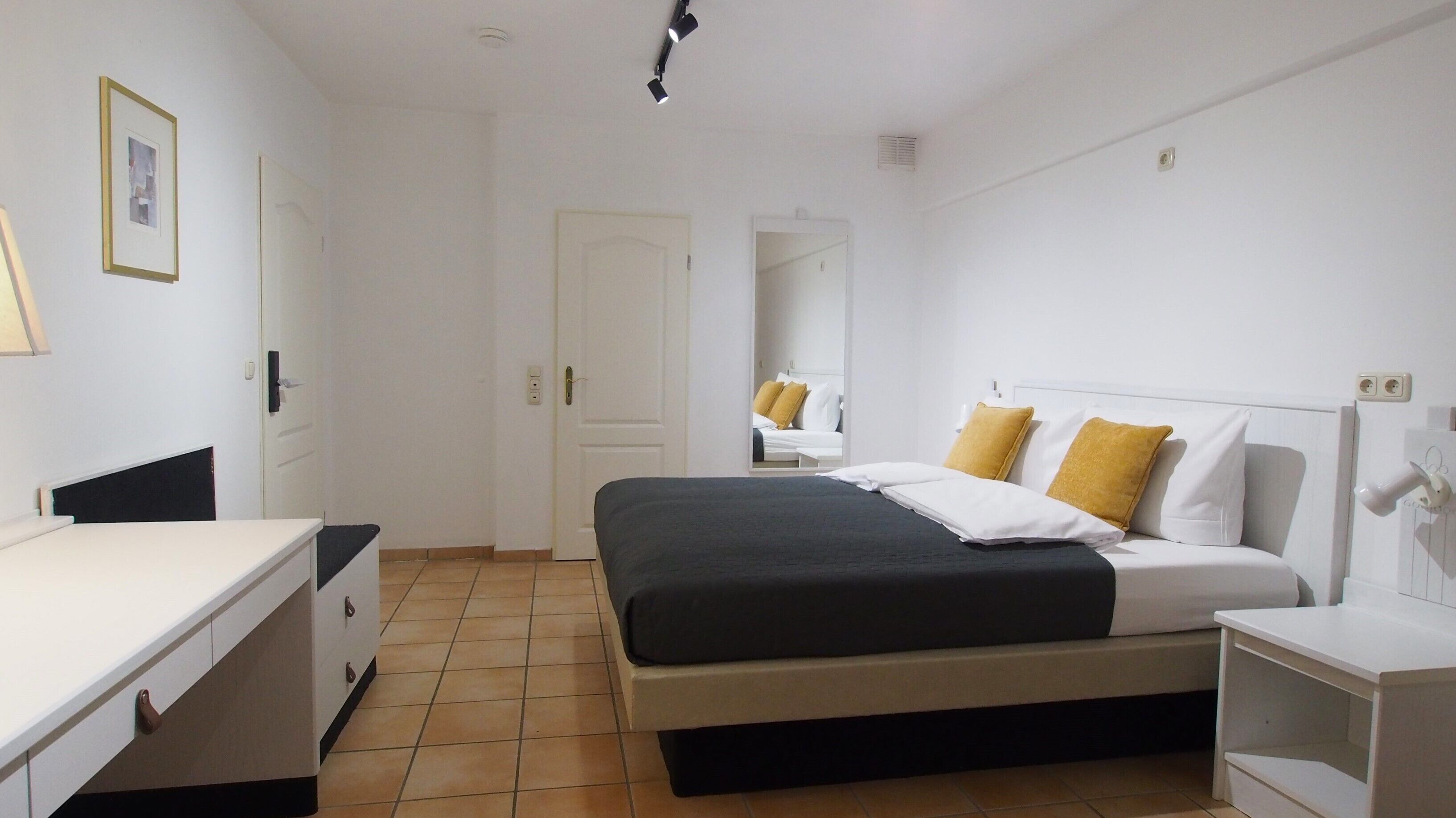A bedroom with a bed, bedside tables, a desk, and a chair.