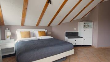 A bedroom with a bed, nightstands, a wardrobe, and a ceiling with wooden beams.