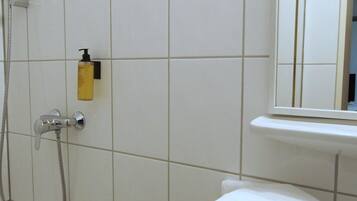 Un bagno con piastrelle bianche, una doccia, un lavandino e uno specchio.