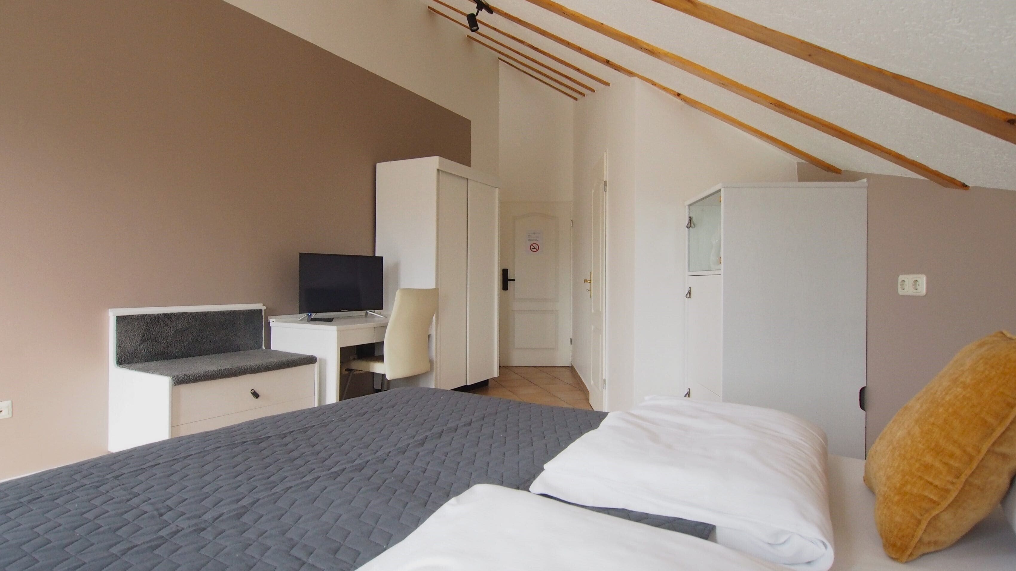 Una camera da letto con un letto, una scrivania con un computer, una televisione e un armadio.