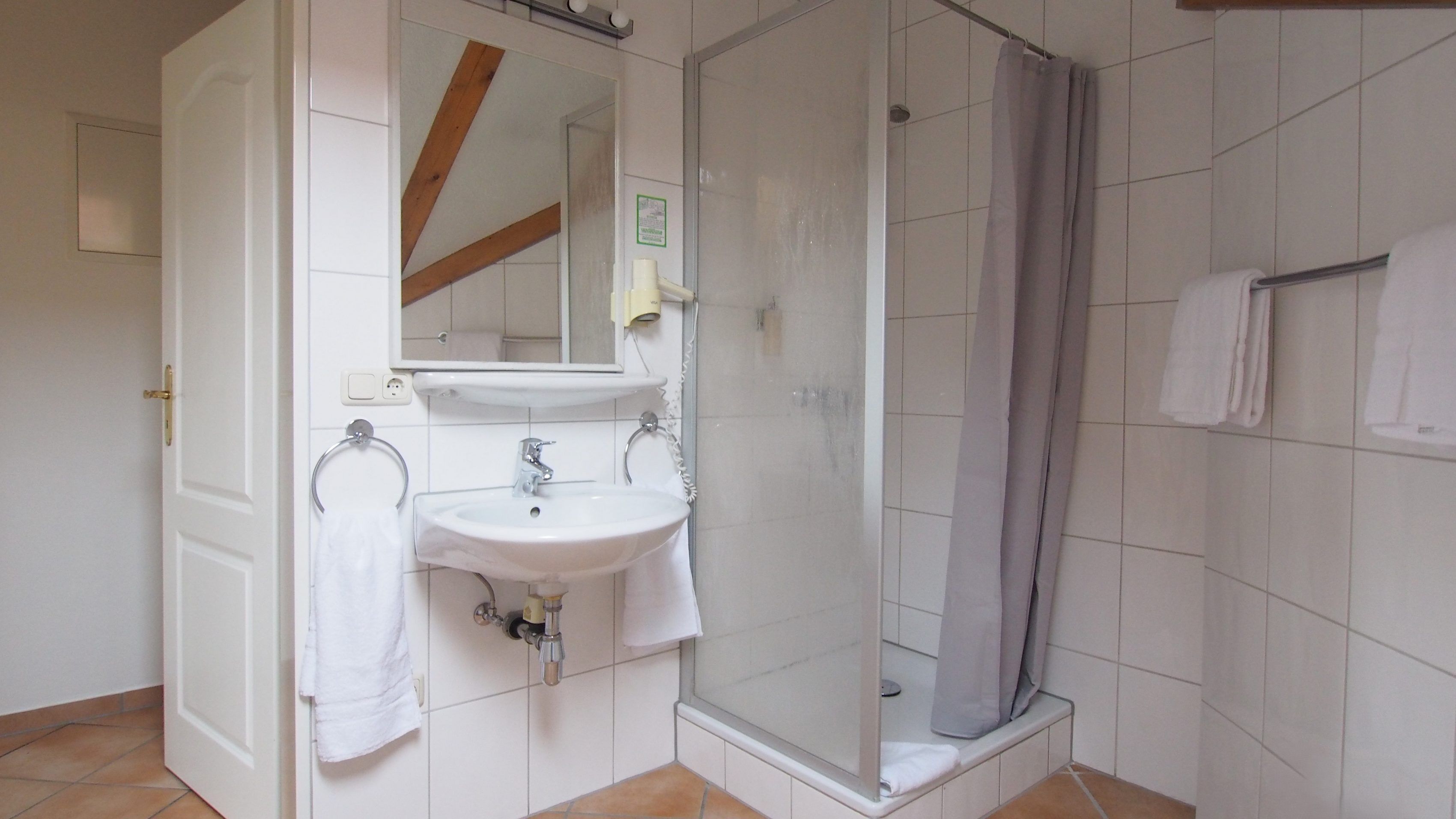 Un baño con lavamanos blanco, espejo y ducha.